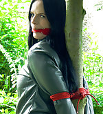 Leather brunette roped to the tree